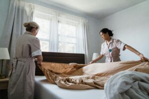 pexels-photo-9462333-9462333 Two housekeepers professionally making a bed in a bright, comfortable room.